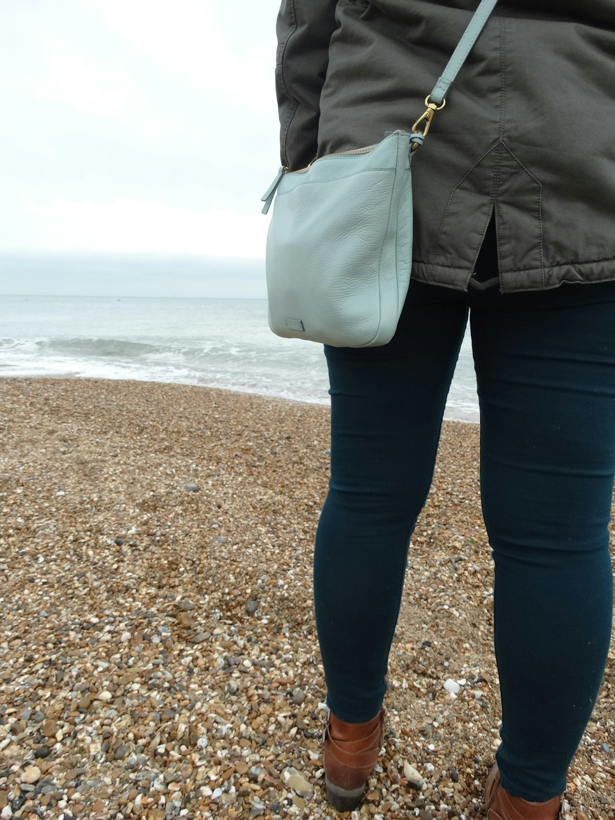 a person standing on a beach holding a purse