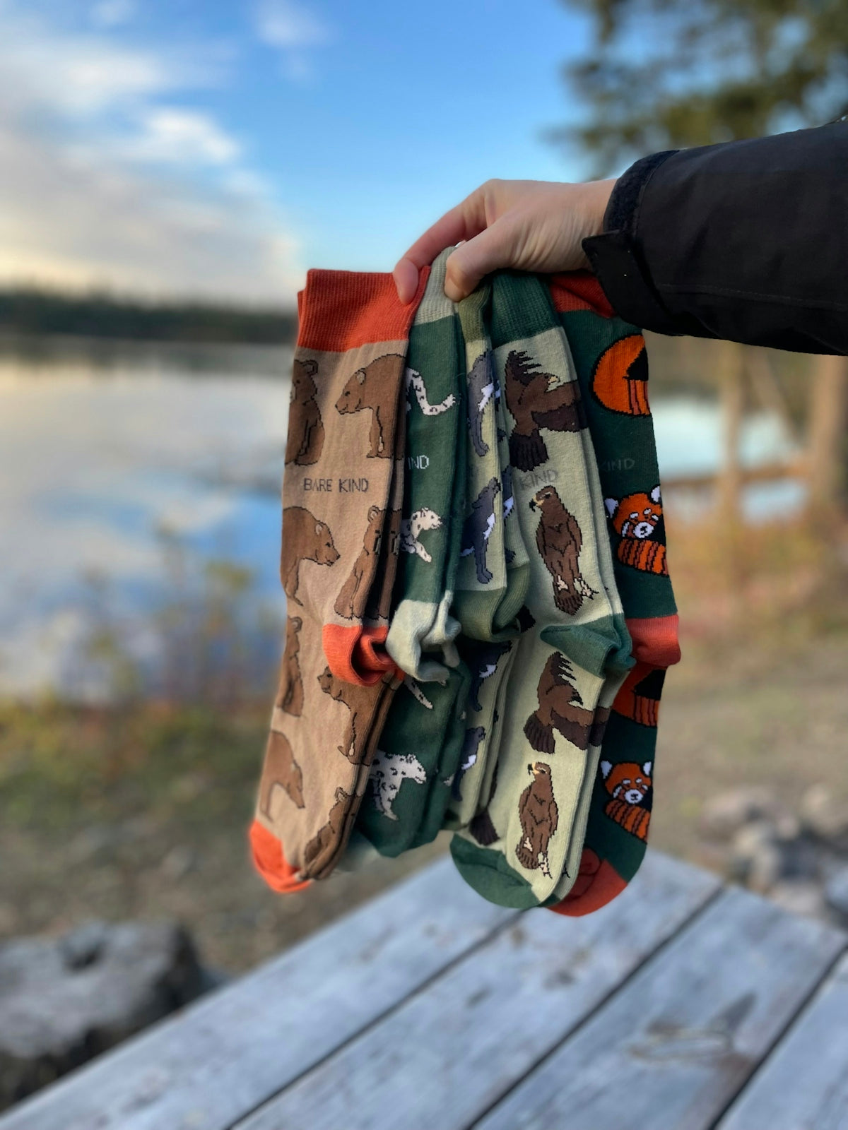 A person holding a pair of oven mitts on a picnic table