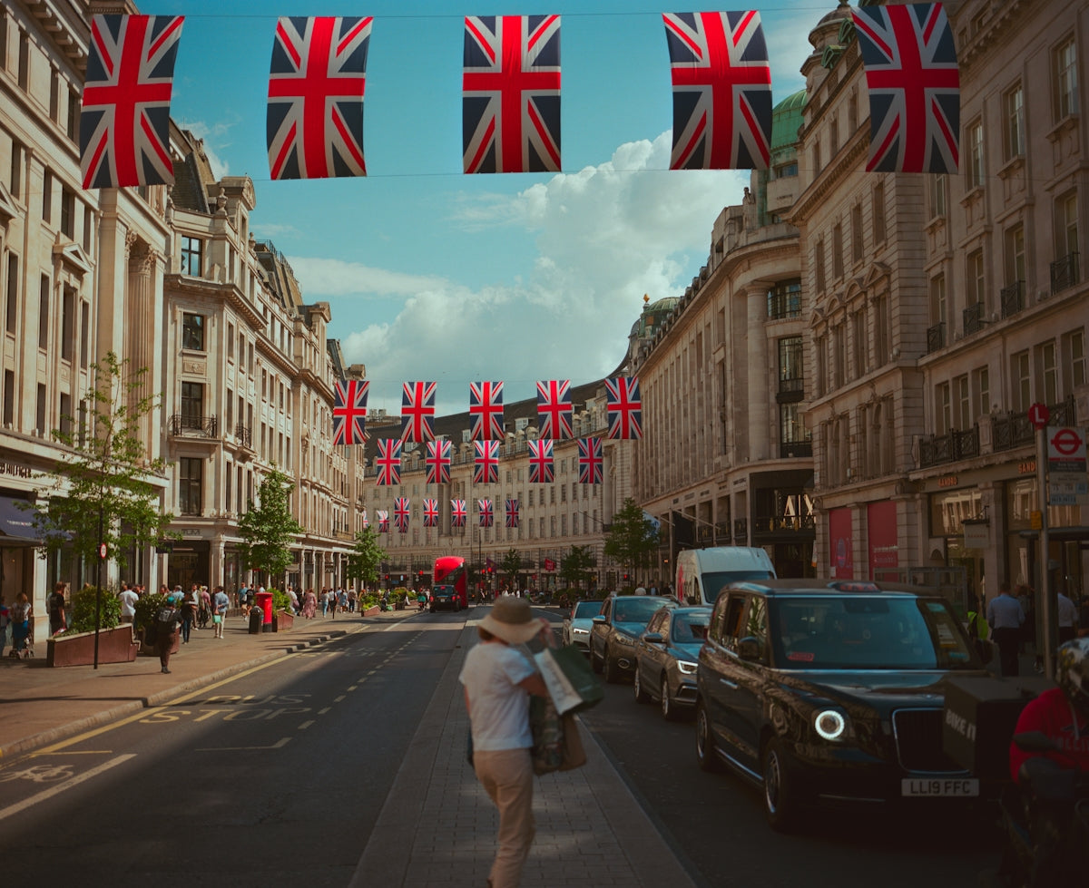 Union jack flags adorn a london street with people.