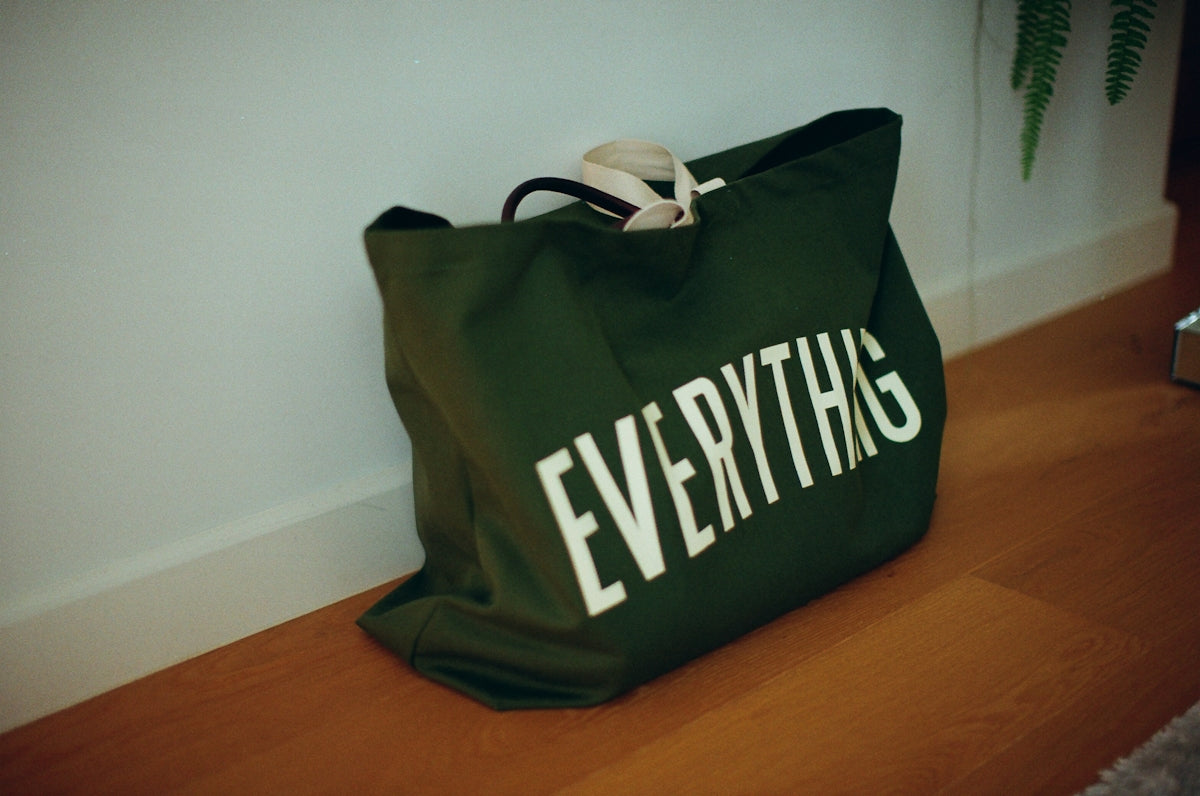 Green canvas bag with everything written on it.