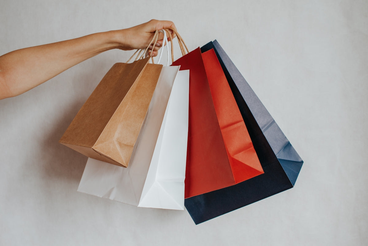 Hand holding colorful shopping bags against a light background